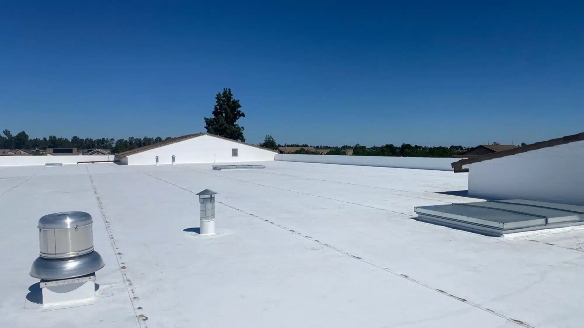 Commercial building roof installed with TPO roofing membrane showing heat-welded seams and reflective surface for energy efficiency