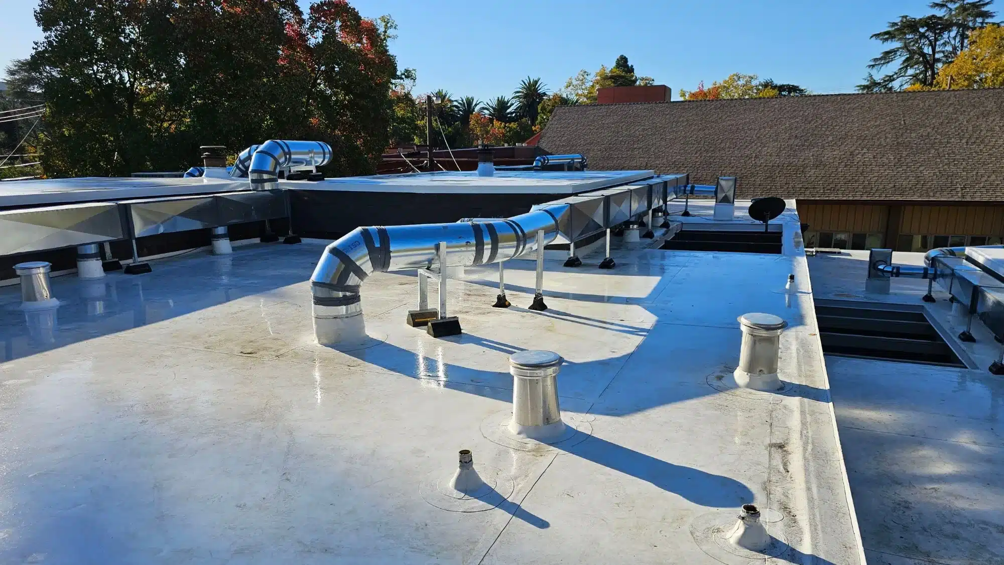 Commercial flat roof protected with a reflective roof coating, featuring HVAC ductwork and ventilation systems designed to help extend roof life.