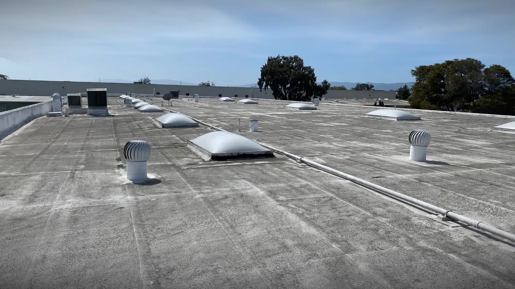 Weathered commercial flat roof with vents and skylights showing potential damage that may require roof repair in Modesto, CA.
